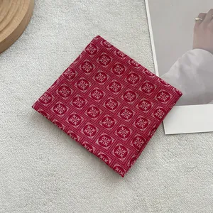 Close-up of red floral cotton linen scarf with geometric pattern on wooden tray
