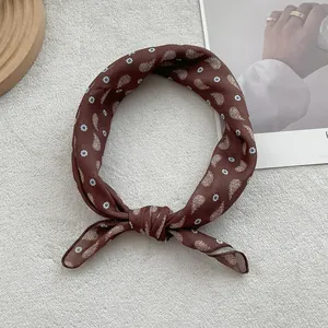 Detailed view of dark brown paisley silk scarf tied in a knot on white fabric background