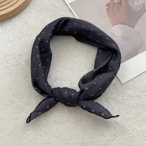 Detail of silk-like dark blue square scarf with white polka dots tied in an elegant knot