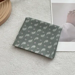Detail view of cotton paisley bandana in sage green on soft white plush background