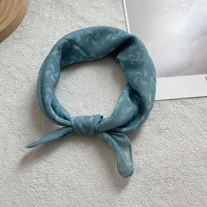 Teal paisley print silk scarf in ring-knot style on elegant white velvet background