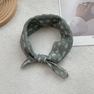 Close-up of retro dark green paisley print scarf tied in a knot on knit background