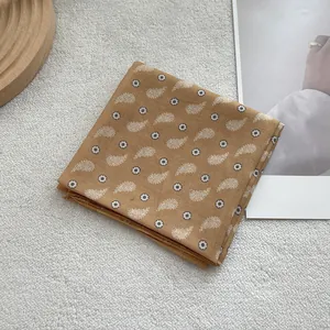 Detail of camel paisley cotton bandana with intricate white patterns and finished edges