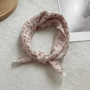 Detail of pink paisley silk scarf on wooden tray showing soft fabric texture and pattern