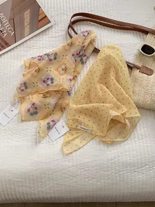 Detailed flat lay of cotton linen scarves featuring strawberry floral and polka dot patterns
