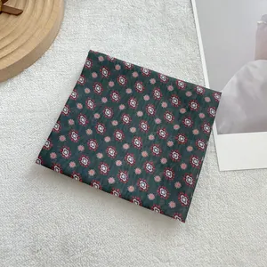 Detail van een gevouwen katoenen sjaaltje met retro bloemenprint op donkergroene basis