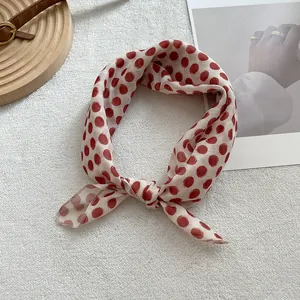 Detailed view of polka dot silk scarf tied in a bow on a decorative wooden tray