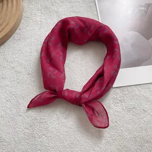 Close-up of deep red silk scarf featuring grey paisley print and detailed hem finish