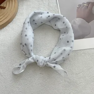 Detail of soft white square scarf with classic black polka dots tied in a stylish knot