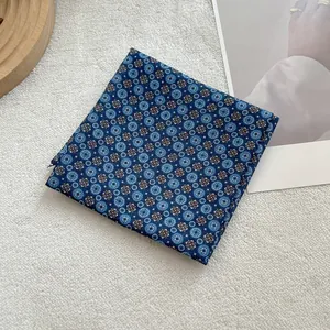 Detail shot of blue floral cotton linen square scarf on a soft white plush background