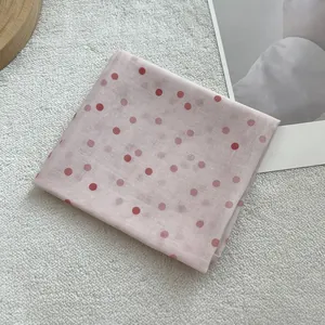 Detail view of light pink cotton linen square scarf with red polka dots on white rug