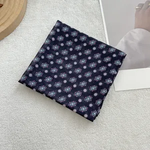 Detail van een marineblauwe katoenen vierkante sjaal met bloemenprint op wit pluche