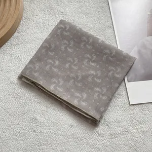 Detailed view of light taupe cashew print silk scarf with fine stitched edges and mesh texture