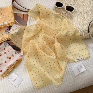Detail of yellow polka dot cotton scarf with brand tag on striped fabric background