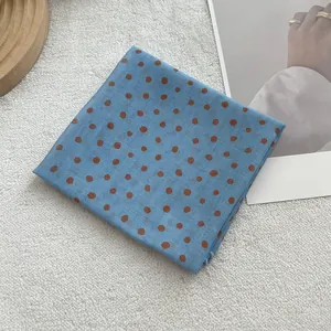 Macro detail of blue cotton linen scarf with brown polka dots on a soft textured surface