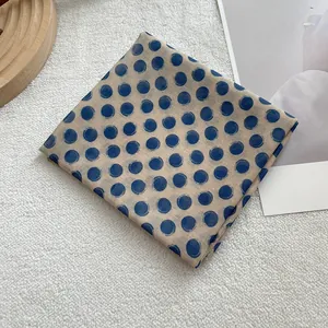 Macro shot of French retro polka dot cotton linen neckerchief on a white textured background