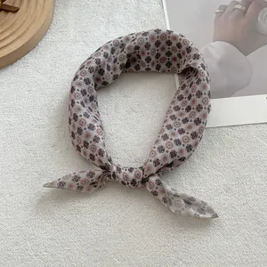 Detail of floral linen-feel scarf with geometric patterns on a soft white texture