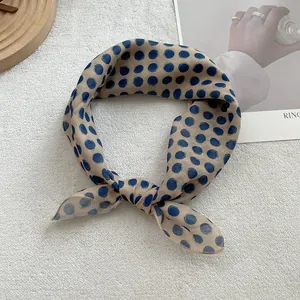 Close-up of elegant polka dot silk scarf tied in a bow on a white textured background