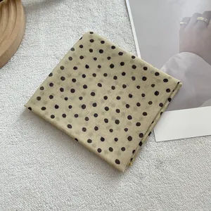 Detailed close-up of a soft cotton-linen polka dot scarf on a textured background