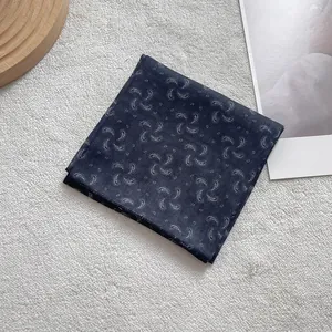 Close-up of navy paisley pattern silk scarf neatly folded on a textured surface