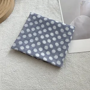 Detailed view of dark grey cotton linen scarf with white polka dot pattern on beige rug