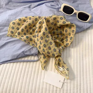 Detailed flat lay of a yellow silk square scarf with blue geometric diamond patterns