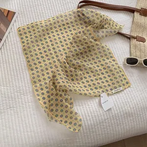Detail of floral print silk scarf with fine rolled edges and premium brand tag