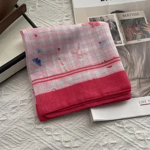 Detail of pink plaid silk scarf with red border and blue butterfly motifs on a book