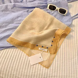 Flat lay of striped cotton linen square scarf with yellow border and blue polka dots