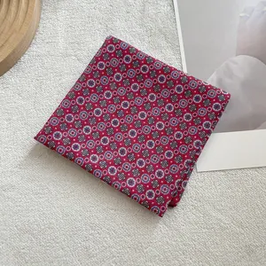 Detailed macro shot of a red cotton linen square scarf with blue floral patterns