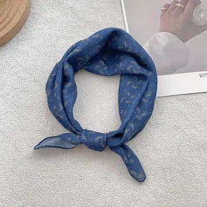 Close-up of a knotted navy blue silk scarf with golden paisley patterns on plush carpet