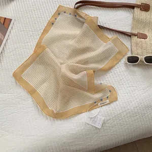 Detail view of yellow striped cotton linen scarf with blue polka dots and product tags