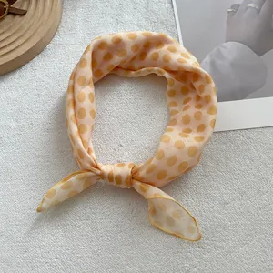 Detailed macro view of retro sunset yellow polka dot linen silk scarf tied in a bow knot