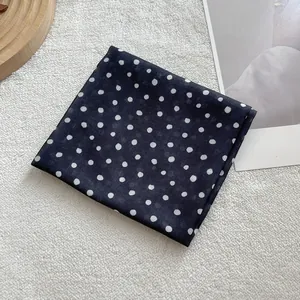 Detail of soft cotton linen square scarf with classic white polka dots on black fabric