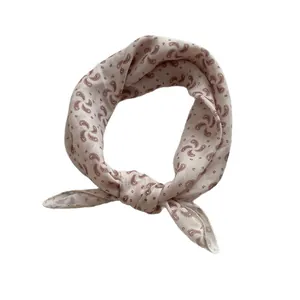 Champagne silk scarf with red paisley print tied in a loop over white background