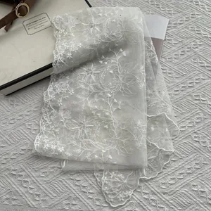 Elegant off-white lace scarf with floral embroidery and pearls on a magazine