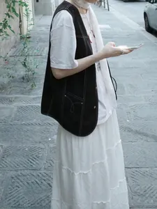 Detail of dark vest with white contrast stitching and arc-shaped pocket embroidery