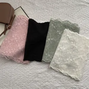 Detail of floral lace embroidery scarves in pink black green and beige with wavy edges