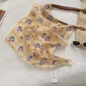 Detail of light yellow silk scarf with strawberry floral print and neat hemmed edges