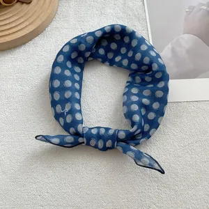 Detailed close-up of a blue polka dot cotton linen neck scarf tied in a neat bow