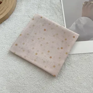 Detail showing soft cotton linen texture of pink square scarf with gold polka dots