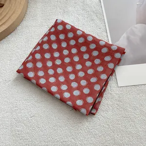 Detail of vintage red polka dot linen-silk scarf folded on a textured background