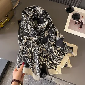 Close-up of black and white paisley scarf with wide beige borders on a stylish setup