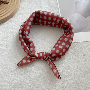 Detailed view of retro brick red silk scarf with blue polka dots tied in a bow