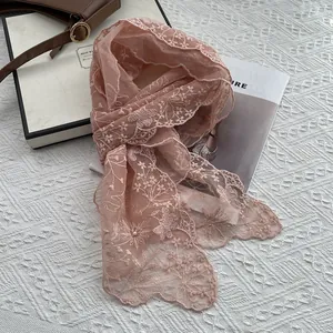Close-up of light pink lace scarf with floral embroidery, white pearls, and sequins