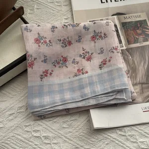 Detail of floral printed silk scarf with light blue checkered border and rolled hem edge