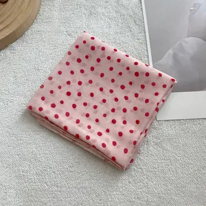 Detailed close-up of soft pink linen cotton scarf with red polka dots and fine edge stitching
