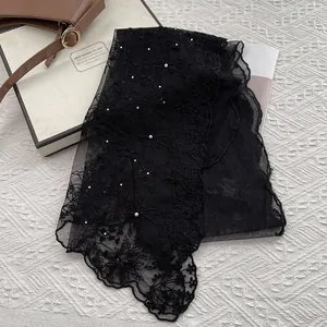 Macro shot of black lace scarf featuring white pearls, rhinestones and scallop edges