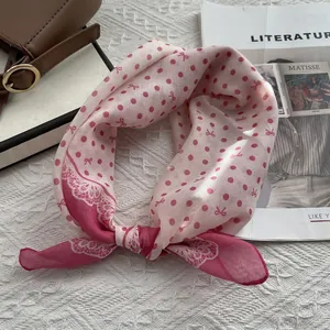 Detail of pink polka dot neck scarf with lace trim on a textured woven background