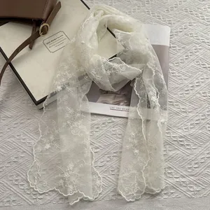 Close-up of elegant floral lace embroidery and scalloped edges on the white mesh scarf
